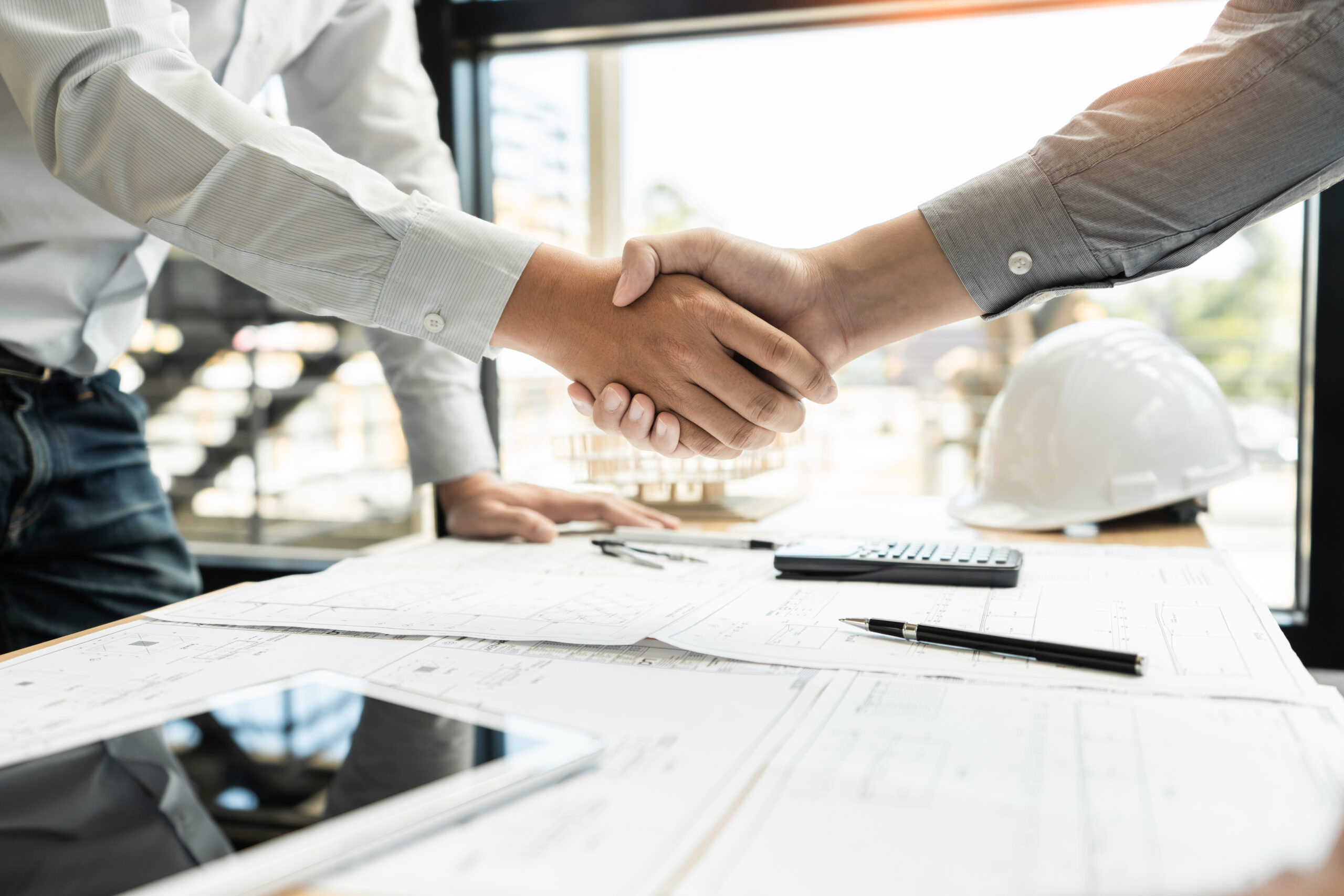 Architect and engineer construction workers shaking hands